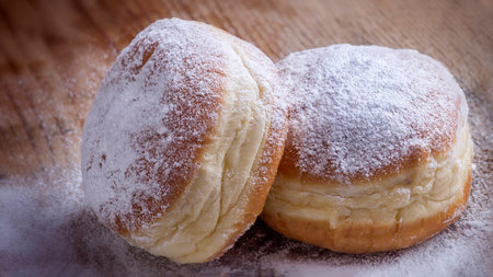 Freshly baked donuts with powdered sugar on a wooden board.