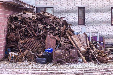 Pile of scrap metal in front of an old abandoned building.の写真素材
