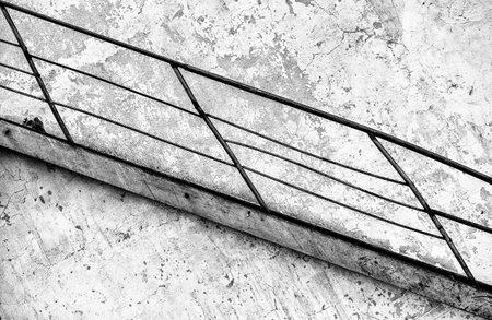 Black and white image of a metal railing on a concrete wall.の写真素材