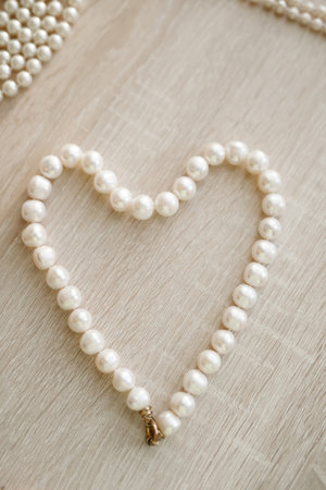 Heart shaped pearl necklace on wooden backgroundの写真素材