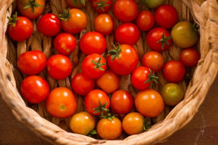 Cherry tomatoes in a wicker basket on a wooden background.の写真素材