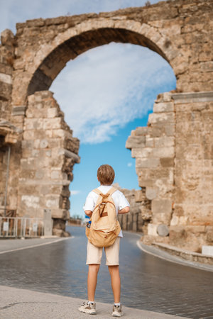 Back view of a little boy with a backpack on the background of the ancient Roman aqueductの写真素材