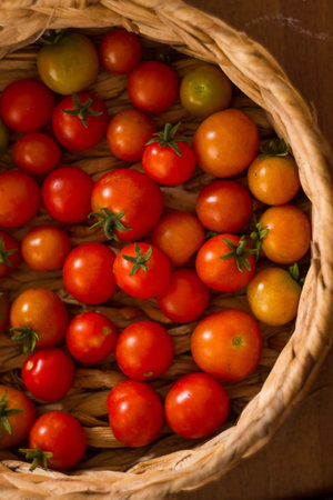 Cherry tomatoes in a wicker basket on a wooden background.の写真素材