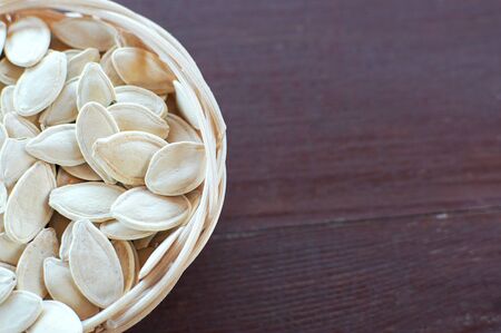 Unpeeled pumpkin seeds in a wicker plate. On a gray backgroundの写真素材