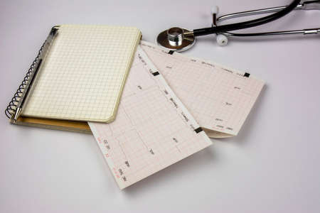 Stethoscope, notepad and electrocardiogram sheets. Cardiologist doctor's desk. Medicine and health...