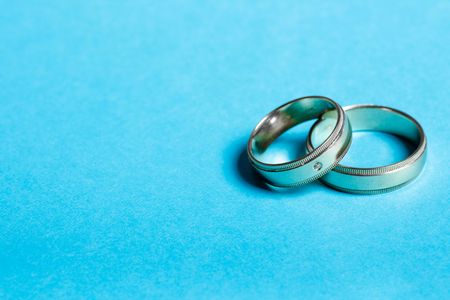 pair of wedding bands isolated on cyan background macroの写真素材
