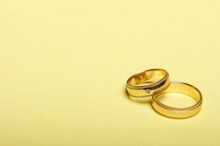 pair of wedding bands isolated on yellow background macroの写真素材