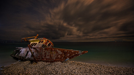 stranded rotten ship fisher boat in dramatic cloud and full moon sceneの写真素材