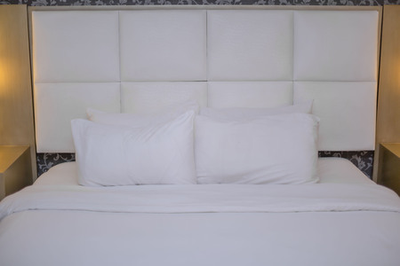 Bedroom furniture king size bed in clean white bedding's and pillows with bedside lamps
