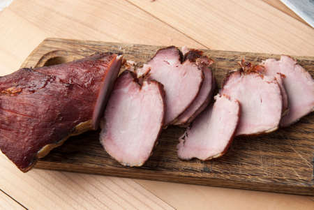Smoked meat on wooden cutting board, close upの写真素材
