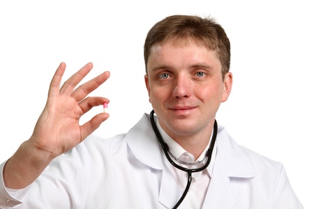 Portrait of thoughtful male doctor holding a pill on white backgroundの写真素材