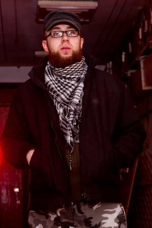 young bearded terrorist with a gun in the stroma of a dilapidated shelter, the basement of the old buildingの写真素材