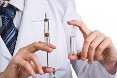  doctor holding at a syringe with some cure or a toxic material inside isolated on white backgroundの写真素材