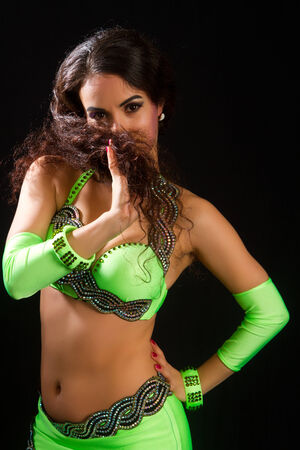 beautiful young brunette in a green suit oriental dance on black の写真素材
