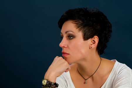 girl with short hair wearing a white t-shirt and jeans against a dark background