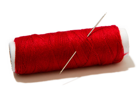 skein of red thread with a needle for sewing isolated on white backgroundの写真素材