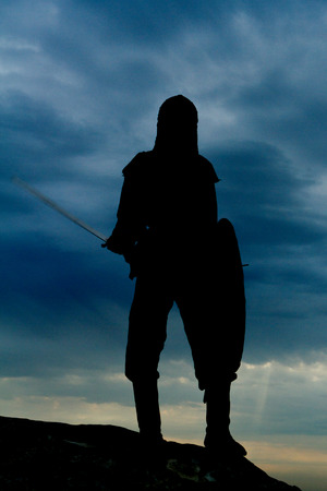 Knight  on a rock with a sword against blue cloudy skyの写真素材