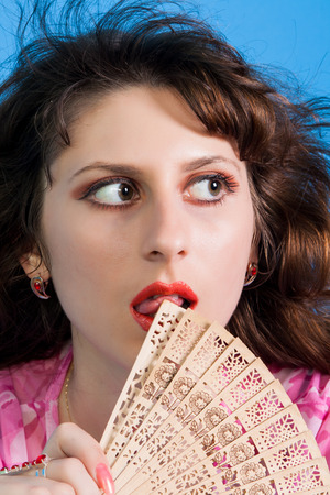 portrait of a beautiful young brunette in a pink dress on a  blue backgroundの写真素材