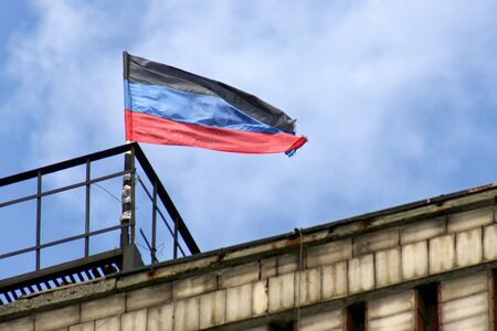 Donetsk Republic flag located on one of the buildings of Donetsk on background the skyの写真素材
