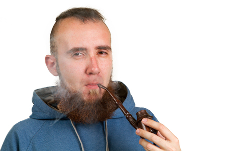 young bearded guy smoking a pipe on a light backgroundの写真素材
