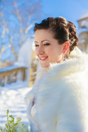 bride posing in the winter forest in a fur coat. Wedding photo session in a snowy Park.の写真素材