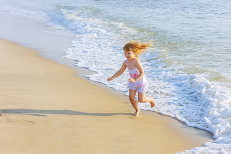 little girl on the beach running in the waterの写真素材