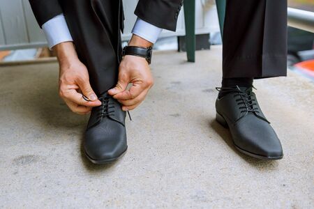 Hands of wedding groom getting ready in suit putting his wedding shoes.の写真素材