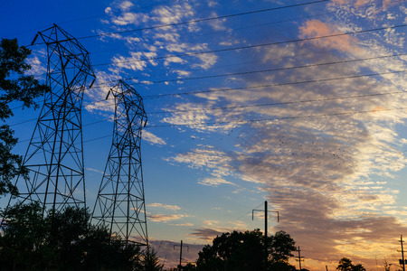 High voltage power pylons in sunset scene sunset sky sun electricity cableの写真素材