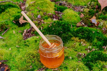 Full honey pot and honey stick with summer flowers on rustic wooden background, selective focusの写真素材