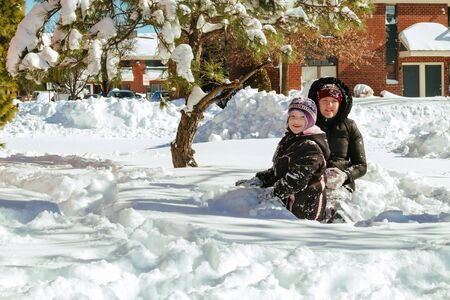 two little girls playing on the snow children play in winter with snowの写真素材