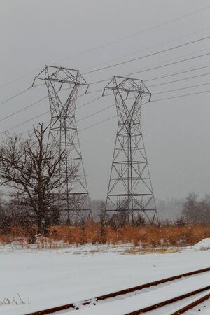 Power lines in winter scenery, electrical tower in wintertime with snow covered fieldsの写真素材