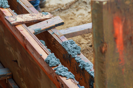 Closeup of foundation excavation with fresh poured concrete and embedded steel reinforcement bars to form continuous footingの写真素材