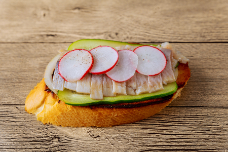 Small sandwiches with vegetables, fish cucumber onion radish sandwich herring wooden background. Top view.の写真素材