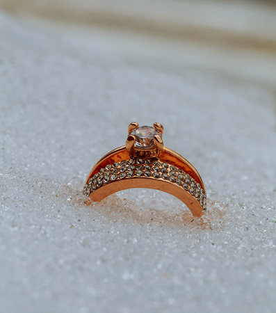 Red heart in snow with wedding rings. gold wedding ring in the snowの写真素材