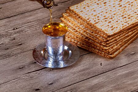 passover matzo with kiddush cup of wine on wooden table