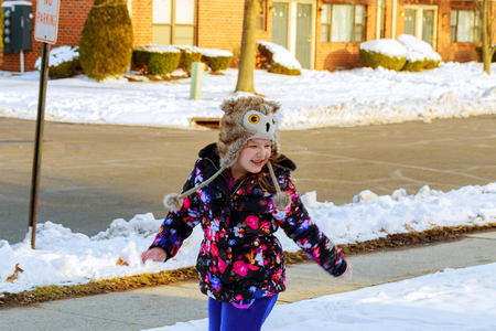 Little girl shoveling snow on home drive way. Child with shovel playing outdoors in winter season.の写真素材
