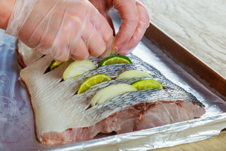 Marinated fried fish fry with spices n lemon filets in oil with lemon and onion dish in the ovenの写真素材