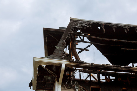 Rescuers firefighters extinguish a fire on the roof. The building after the fire. Burnt window. Ruined house. Catastrophe. Soot on the windowsの写真素材