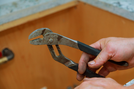 Man mechanic in working clothes holds a wrench in his hand The master holds a gas key in his handsの写真素材