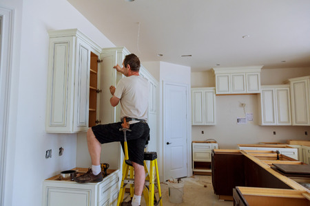 Installation of kitchen. Worker installs doors to kitchen cabinet. Installation of doors on kitchen cabinetsの写真素材