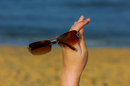 woman holds sunglasses in the hands of the oceanの写真素材
