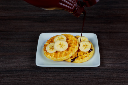 Tasty Belgium waffles lying on a plate with strawberries and chocolate syrupの写真素材