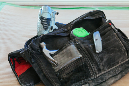 Working bag with a roulette hammer Carpenters bag with full of tools, wooden tableの写真素材