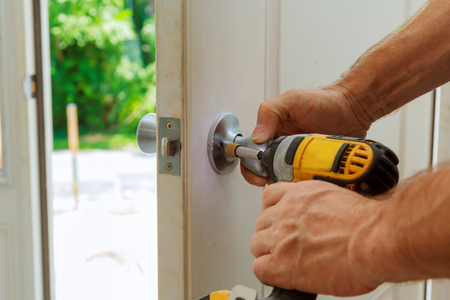 Installation of a lock on the entrance door Hand 's man with screwdriver Installs door knob.