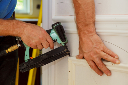 Home Improvement Carpenter brad using nail gun to Mouldingの写真素材