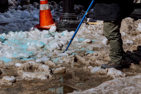Cleaning the yard of snow. man in a jacket and boots, holding a plastic shovel with snow, Workers sweep snow from road in winter, Cleaning road from snow storm, Selective focusの写真素材