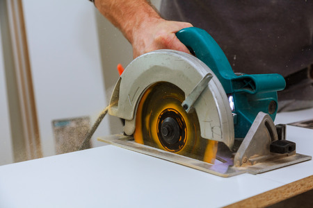 Construction worker using slider compound mitre saw or circular saw for cutting massive wood board. Details of construction, renovation worksの写真素材