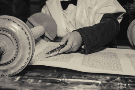 Reading a Torah scroll during a bar mitzvah ceremony with a traditional yad pointing towards the...