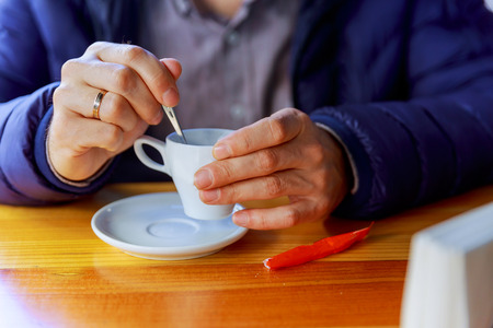 man with cup of coffee. Young male person in casual clothes having hot drink in cafe and looking at window on bright sunny dayの写真素材