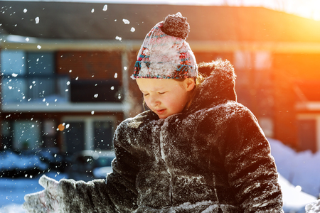 Happy little girl in white mittens walking in the winter park throws up snow Kids play outside winter seasonの写真素材